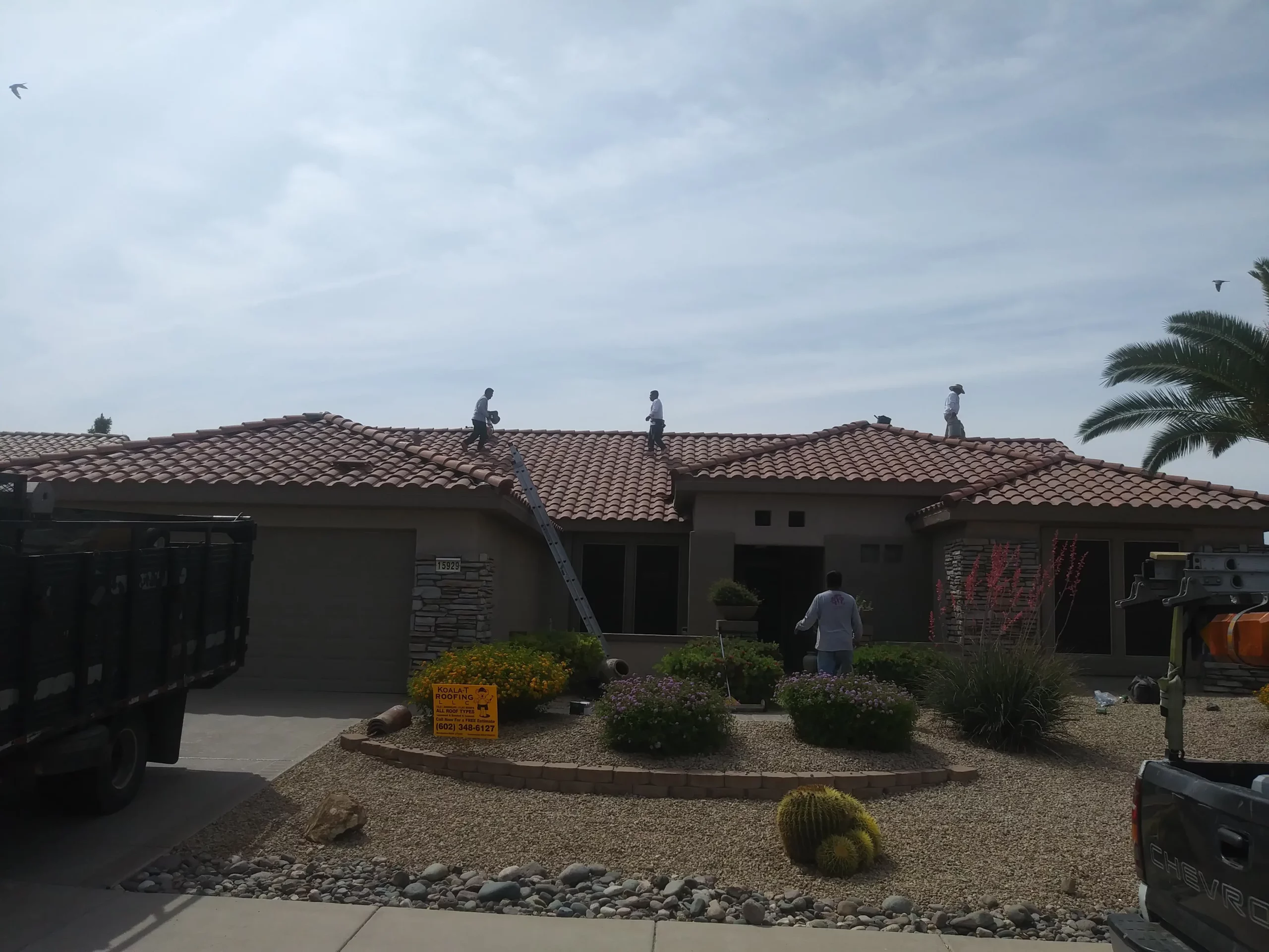 Roofers working on a residential tile roof, performing maintenance and repairs to ensure optimal condition.
