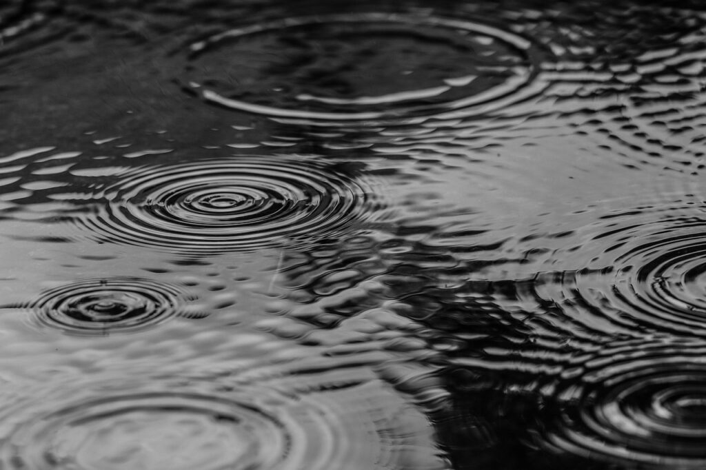 Black and white image showing ripples on a water surface, symbolizing the importance of effective waterproofing to prevent water intrusion in roofing structures.