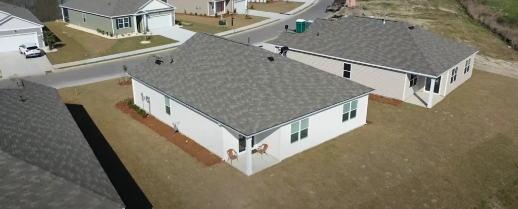 Aerial view of a suburban neighborhood showcasing several single-story homes with new asphalt shingle roofs, emphasizing uniform installation and curb appeal in a residential development.