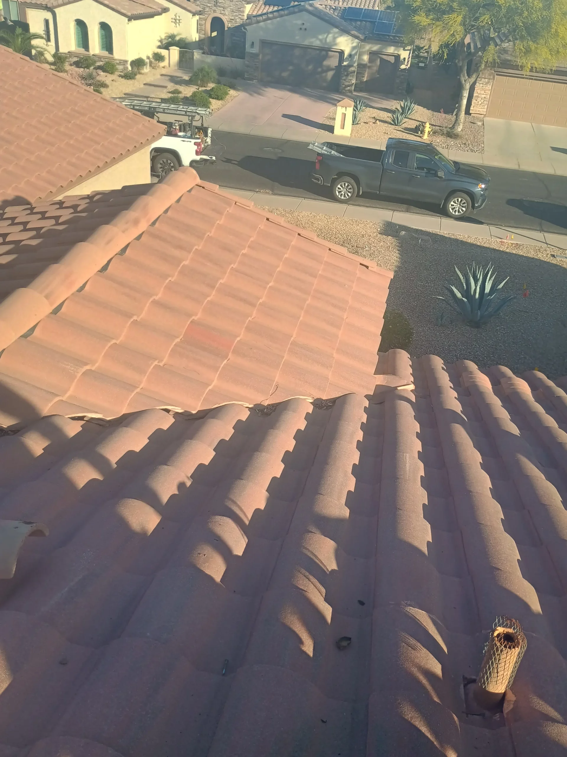 Close-up view of a Arizona residential tile roof with visible lifted and misaligned tiles, showing the need for repair or replacement.