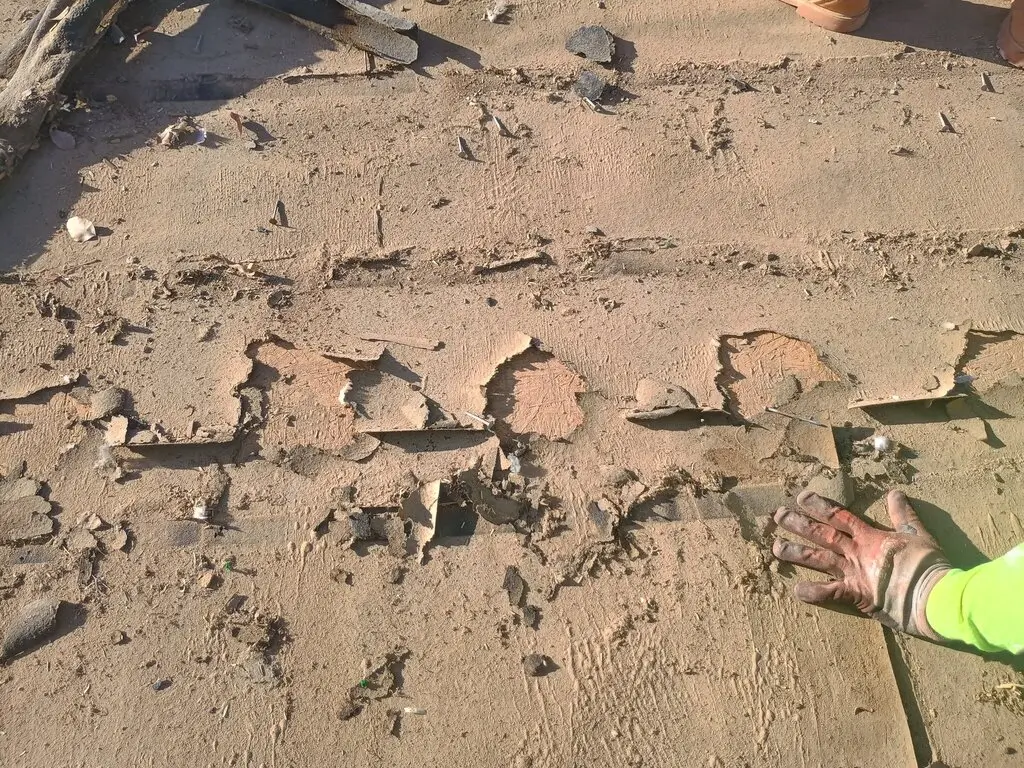 Damaged roof decking exposed during roof tear-off, showing repair needs that increase roofing costs