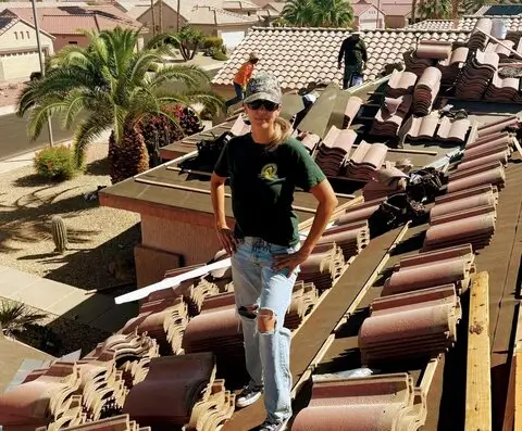 Roofing contractor standing on residential roof during tile replacement project