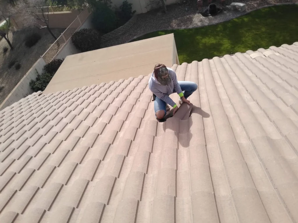 Roof inspector examining broken tile on residential roof during inspection