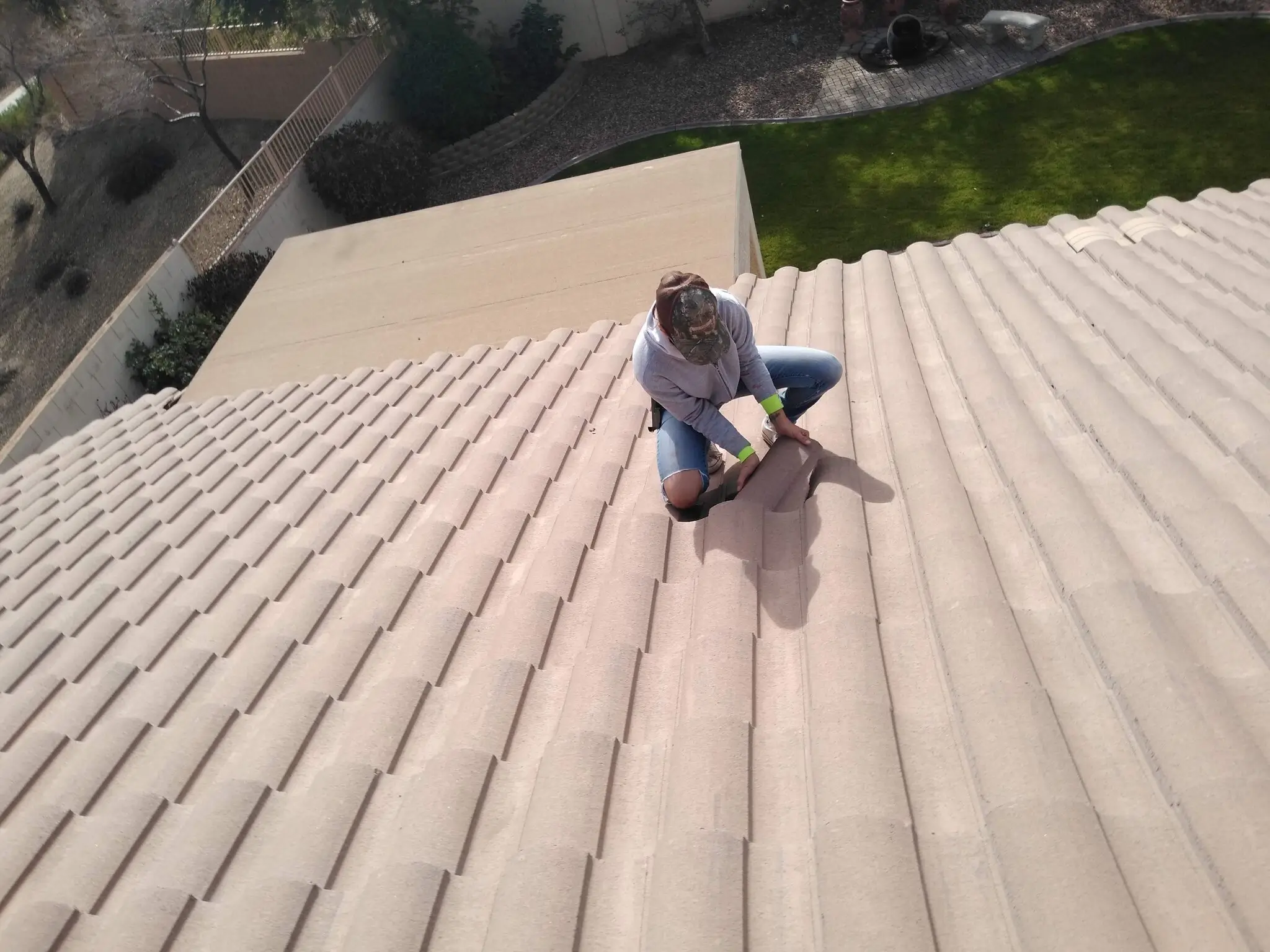 Roof inspector examining broken tile on residential roof during inspection
